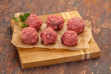 Raw meatball over wooden background