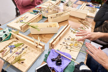 A woman lays out a composition. Master class on creating frame with Herbarium in tiffany technique...