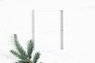 Christmas composition. Fir tree branch, photo frame on marble background. Christmas, winter, new year concept. Flat lay, top view