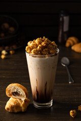 Tall glass cup with chocolate milkshake and caramel popcorn and chocolate muffin on wooden background