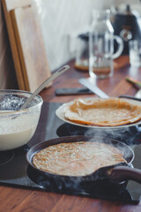 Baking pancakes in a frying pan close-up, ready-made pancakes on a plate.