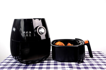 a black deep fryer or oil free air fryer appliance is on the table in the kitchen with white cement wall background