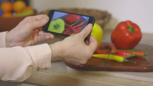 Woman holding smartphone and filming slow motion video of vegetables