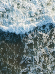 Aerial top down view of foaming waves in sea, ocean. Summer vacation, water surface, scenic seascape. Natural background texture wallpaper