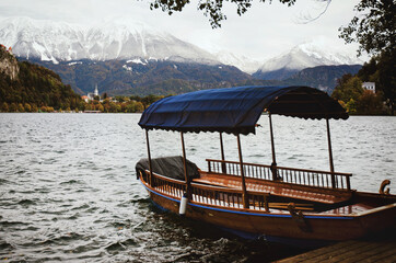View of the snow-capped Alps mountains against the backdrop of lake Bled with tourist boats.