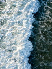 Fototapeta na wymiar Aerial top down view of foaming waves in sea, ocean. Summer vacation, water surface, scenic seascape. Natural background texture wallpaper
