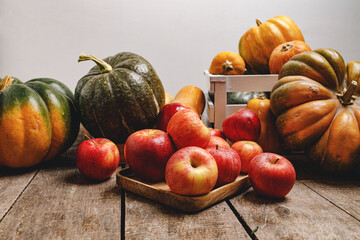 Pumpkins and red apples on wooden background