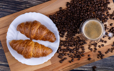 Croissants with a cup of coffee on a wooden board.