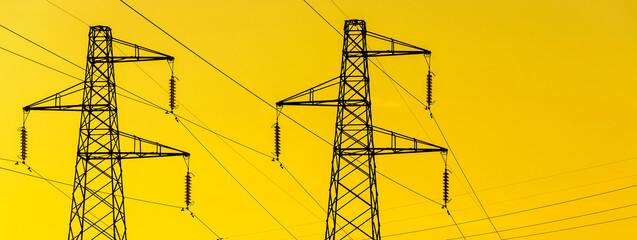 Energy Transmission towers or electricity pylons with wires, cables against golden sky
