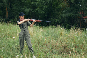 Woman soldier He is holding a gun in a green hunting overalls fresh air 
