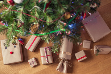 Hand made gift wrapping in a kraft paper under christmas tree. Presents for family. Top view. Flat lay.
