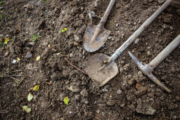 Dirty shovel, pickaxe and spade lying on the ground. Tools for seasonal garden work and for digging at construction site.