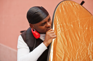 Young professional african american videographer holding professional camera with pro equipment. Afro cameraman wearing black duraq making a videos.