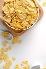 Top view of corn flakes bowl with milk on white background.