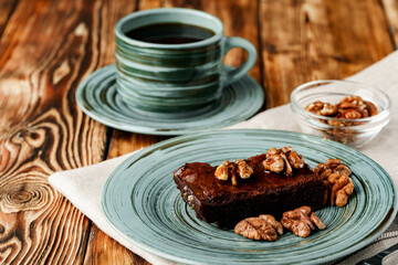 Piece of chocolate cake with nuts on green plate