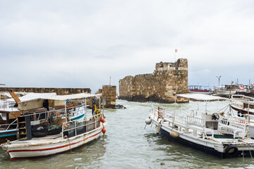 Fototapeta na wymiar Small boats at Byblos harbor with ruins in the background, Jbeil