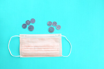 On a turquoise background, a surgical mask and money.
Russian coins.