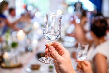 Wedding or party concept. Hand with a glass of vodka guest makes a toast, raising a glass