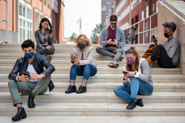 Group of people connected to smat phones reading pandemic news, maintaining social distance for contagion prevention, the new normal social gathering in coronavirus time