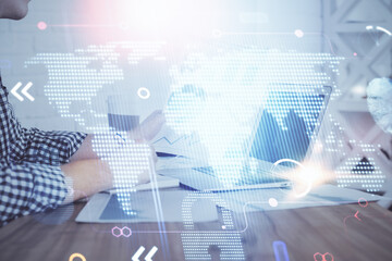 Multi exposure of world map hologram with man working on computer on background. Concept of worldwideweb.