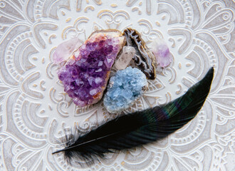 Flat lay view of various crystal geodes amethyst, celestite. With black glowing bird feather.
