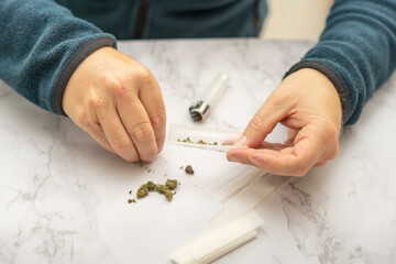 Close Up of man's hands preparing a marijuana and hashish cigar with roller paper
