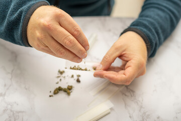Obraz na płótnie Canvas Close Up of man's hands preparing a marijuana and hashish cigar with roller paper