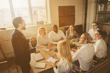 Photo of business people eight diversity age race colleagues sit table share anti crisis crash ideas team professionals discuss 2020 budget improvement aged boss speaking office indoors