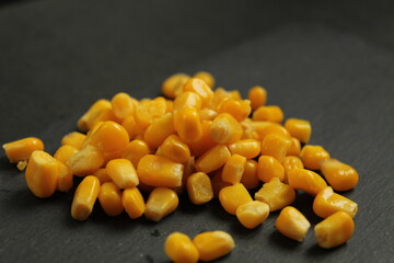 food background sweet sugar yellow corn lying in a pile on a rock dark gray background copy space side view