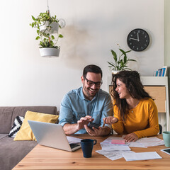 Smiling couple calculating monthly expenses together at home