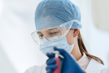 female scientist in a protective mask works in a laboratory.