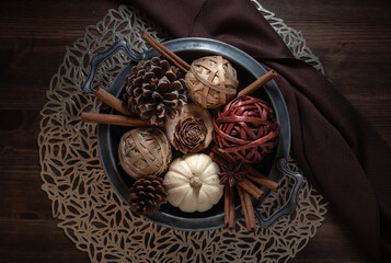 Top down view of a vintage dish filled with autumn ornaments, on a dark wooden table.