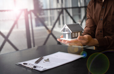 Home insurance concept, home insurance agent can hold a small sample home model. In hand, it...