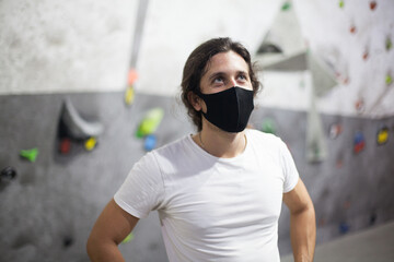 Fototapeta na wymiar young fit male climber wearing mask on steep rock indoors
