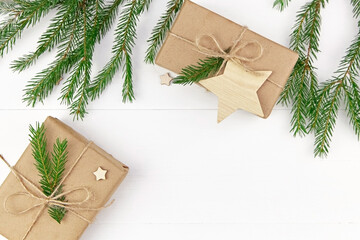 Christmas tree branches and gift boxes on white wooden background.