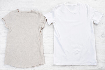 White closeup t shirt mock up flat lay on white wooden background. Male and female shirts. Top view and copy space. Mockup summer t-shirt and summertime. Template blank shirt.