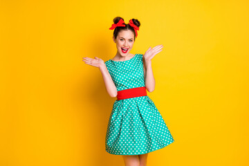 Portrait of charming cheerful girl wearing dotted dress enjoying clapping palms isolated over bright yellow color background