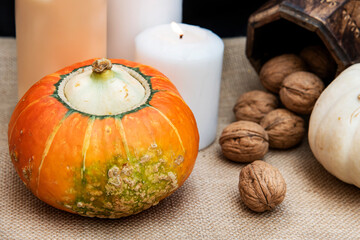 Two organic and healthy pumpkins, three candles, some walnuts and a box on rustic background