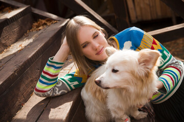 young beautiful woman with dog  sits on a staircase near the house in the autumn outdoor