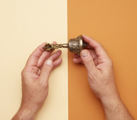 male hands hold a copper Tibetan ritual bell