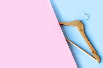 Empty wooden clothes hanger on pastel pink and blue background with copy space. Sale and shopping concept.