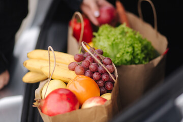 Close-up of groceries in eco package in car trunk. Hands of female packing vegetables and fruits after shipping in supermarket © Aleksandr