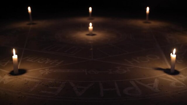 TIlt up shot of The Seal of the Seven Archangels. Illuminated with candles. Dark background. Side view. Scary, mystical occultism.