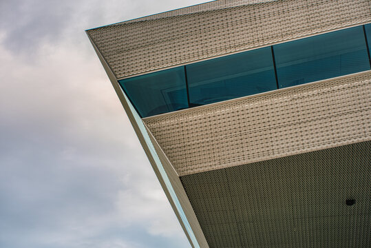  A detailed edge of a contemporary building facade conveys a sense of utter modernity. A sharp corner or edge on a modern library exterior rises against a dramatic sky - Aarhus, Denmark