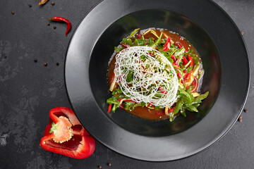 Vegetable salad with arugula, bell pepper, cucumber and flax seeds, on a black background