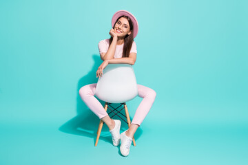Obraz premium Full size photo of nice girlish lady sit on backside chair look in camera isolated over turquoise color background