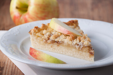 Piece of pie with apples and streusel  on a white plate