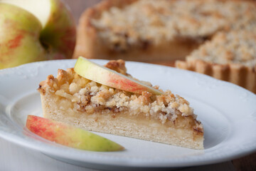 Piece of pie with apples and streusel  and apple wedge on a pie