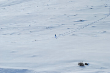 Man and woman walking in snowy mountains. Walking tracks in the snow.