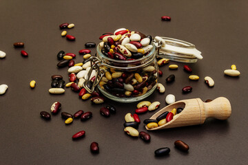 Mix of various dry legumes in glass jar with wooden scoop